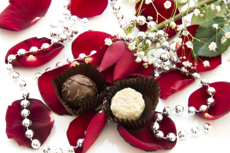 Chocolate and red rose among the rose petalsの写真素材