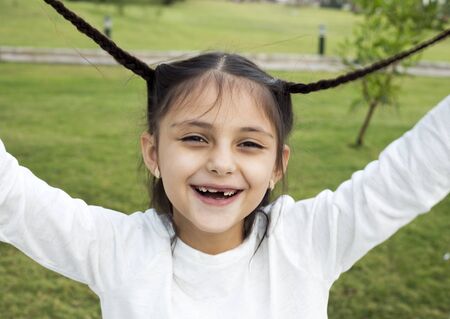 Happy little braided hair girl on green grassの写真素材