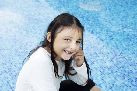 Happy little girl smiling front of the pool