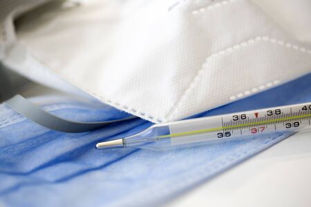 COVID-19 Coronavirus. Fever measurament with degree. Disposable breath filter medical face mask for protection. Dangerous virusの写真素材