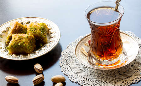 Baklava with walnut and pistachio. Turkish dessert with black arabian tea and traditional silver serving set. Festival of sacrifices. Ramadan holiday.の写真素材