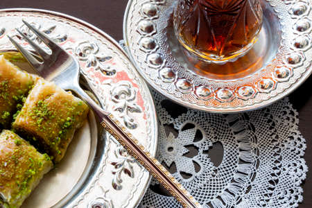 Baklava with walnut and pistachio. Turkish dessert with black arabian tea and traditional silver...