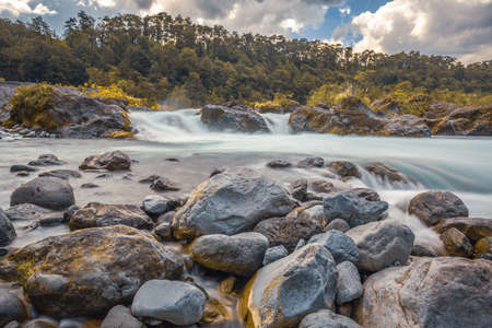 Beautiful Patagonian waterfall in a forest lit by the rising sun of Patagoniaの写真素材