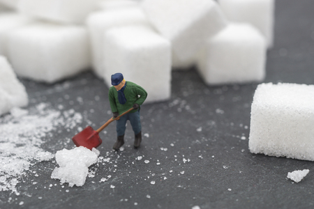 Miniature people sweep up sugar. Health care and snow concept. diet, fat and diabetes. Health care concept.の写真素材