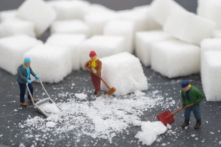 Miniature people sweep up sugar. Health care and snow concept. diet, fat and diabetes. Health care concept.の写真素材