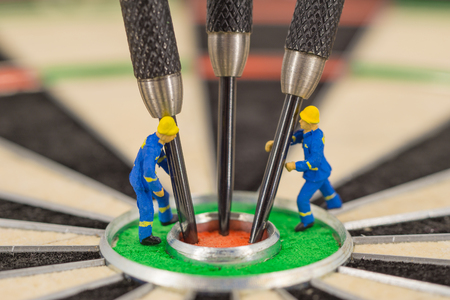 miniature people with dart in bull's eye, close up concept