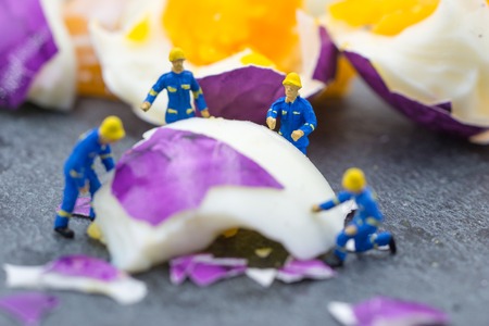 miniature worker people working on egg