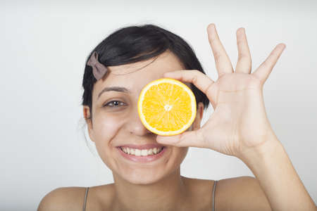 Woman holding orange over eyesの写真素材