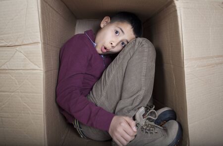 Worried teenage boy sitting in cardboard boxの写真素材
