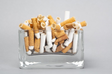 Ashtray full of cigarettes on gray backgroundの写真素材