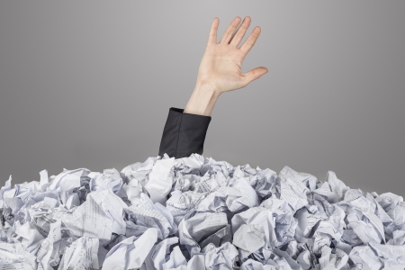The hand reaches out from big heap of crumpled papersの写真素材