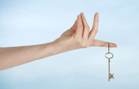 Hand with keys on sky backgroundの写真素材