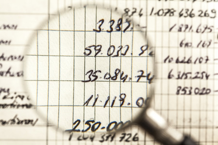 Magnifying glass looking at financial numbersの写真素材