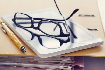 Digital tablet and eyeglasses on fileの写真素材