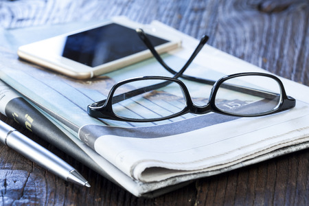 Stack of newspapers with phoneの写真素材