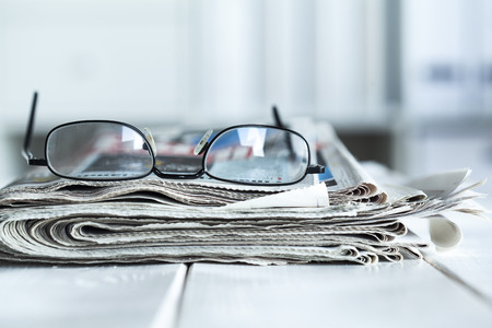 Stack of newspapers and eyeglassesの写真素材