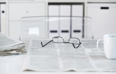 Newspapers with eyeglasses on tableの写真素材
