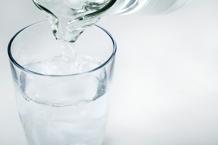 Pouring water on a glass on white backgroundの写真素材