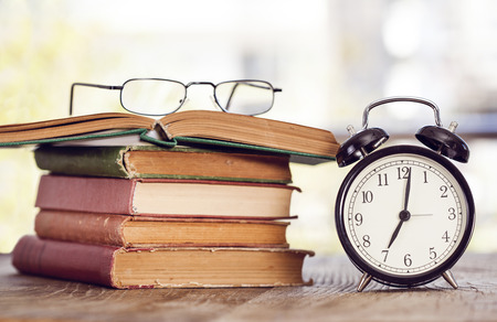 Books with reading glasses on deskの写真素材