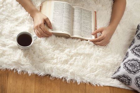 Young woman reading book on carpetの写真素材