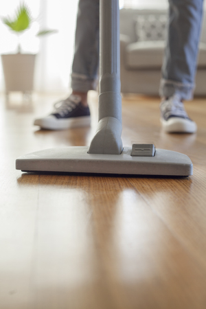 Woman cleaning floor with a vacuum cleaner in roomの写真素材