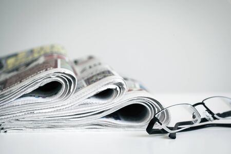 Newspapers with eyeglasses on white background