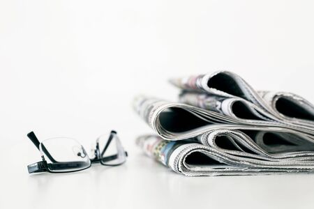 Newspapers with eyeglasses on white backgroundの写真素材