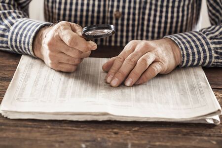 Man reading newspaper with magnifyingの写真素材