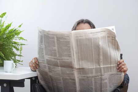 Sitting senior man reading newspaperの写真素材