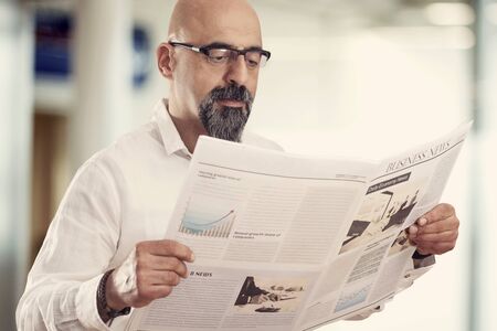 Middle aged man reading newspaperの写真素材