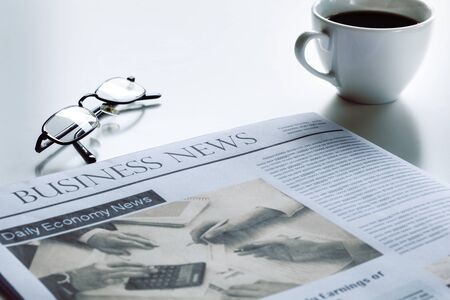 Newspaper with eyeglasses on white tableの写真素材