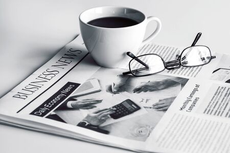 Newspaper with eyeglasses on white tableの写真素材