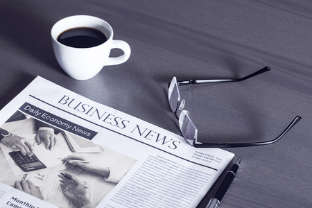 Newspaper with eyeglasses on wooden table