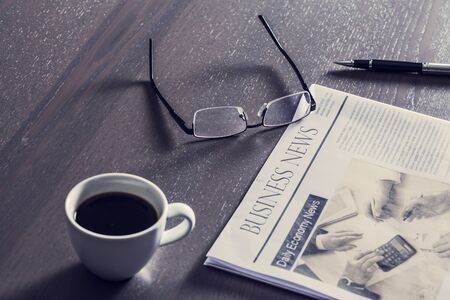 Newspaper with eyeglasses on wooden tableの写真素材