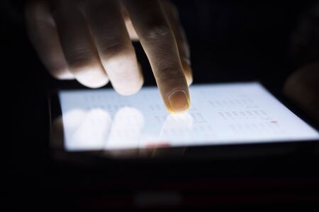 Woman finger touching tablet in darkroomの写真素材