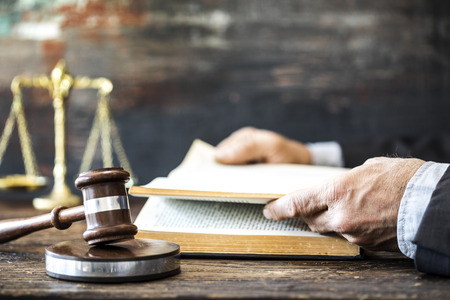 Man reading book with gavel and justice scaleの写真素材