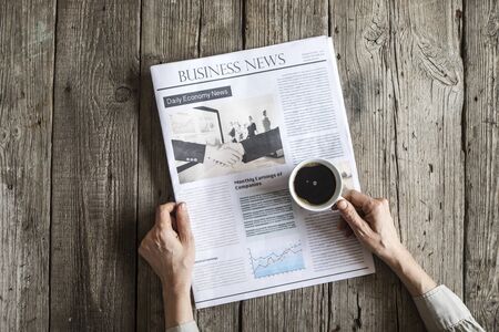 Woman reading newspaper on wooden tableの写真素材