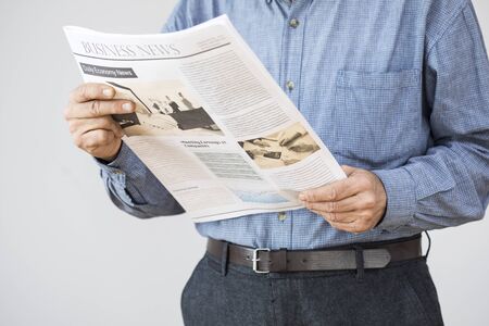 Man hand holding reading newspaper on gray backgroundの写真素材