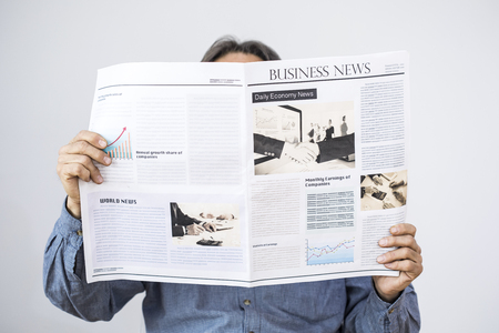 Man hand holding reading newspaper on gray backgroundの写真素材