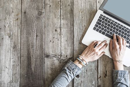 Woman hands using laptop on wooden tableの写真素材