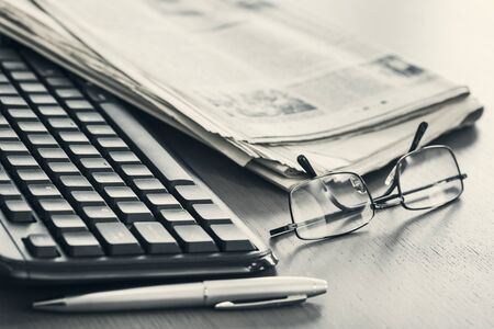Newspaper with keyboard on tableの写真素材