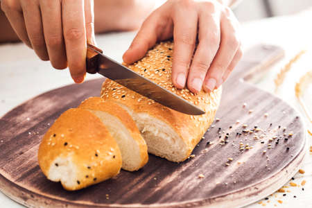 Female hands cutting freshly breadの写真素材
