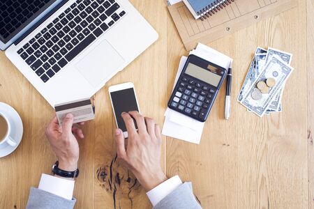 Hands holding credit card and paying bills on table