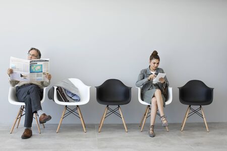 Man reading newspaper and woman using digital tabletの写真素材