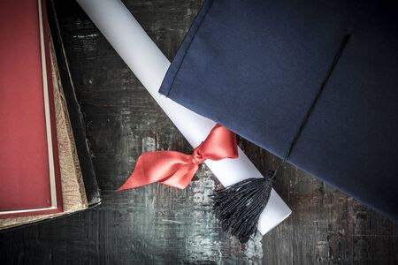 Graduation hat and diploma on tableの写真素材