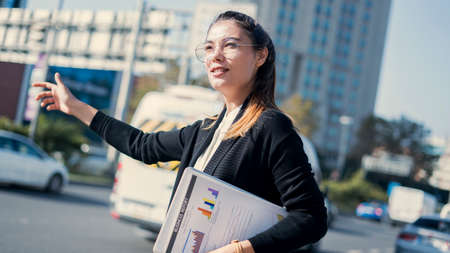 Young businesswoman calls a taxiの写真素材