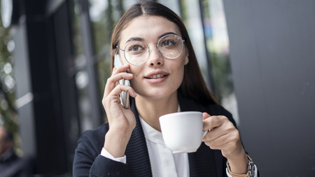 Young woman talking mobile phone and drinking coffeeの写真素材