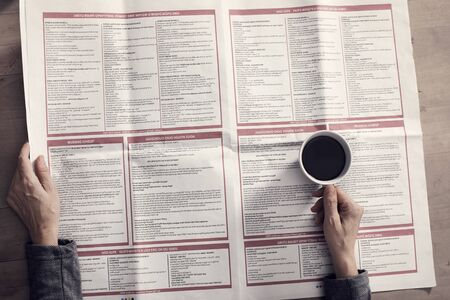 Reading newspaper and drinking coffee on wooden backgroundの写真素材