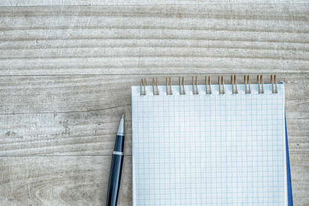 White square spiral notebook next with pen on the table