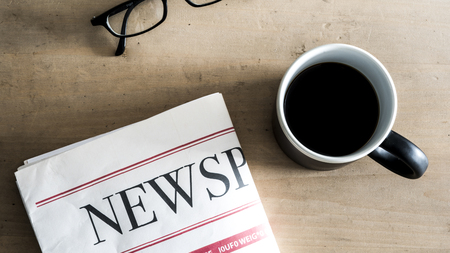 Newspaper, coffee, eyeglass on table